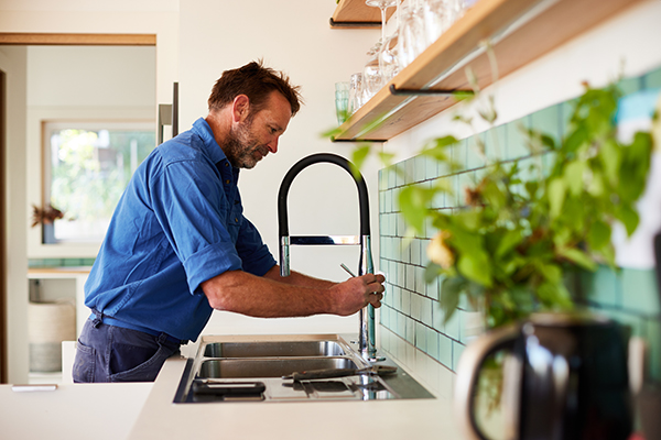 Residential plumbing services in Hobart. Barry fixing a broken tap in kitchen